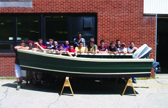 Students in the Tiverton High School marine-trades program show off a 16-foot skiff that they built. © rimta.org
